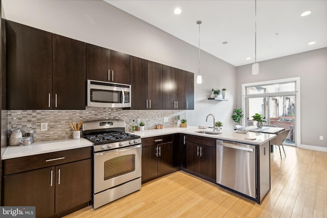 kitchen with appliances with stainless steel finishes, light hardwood / wood-style flooring, hanging light fixtures, and sink