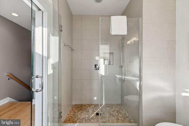 bathroom with hardwood / wood-style floors, toilet, and walk in shower