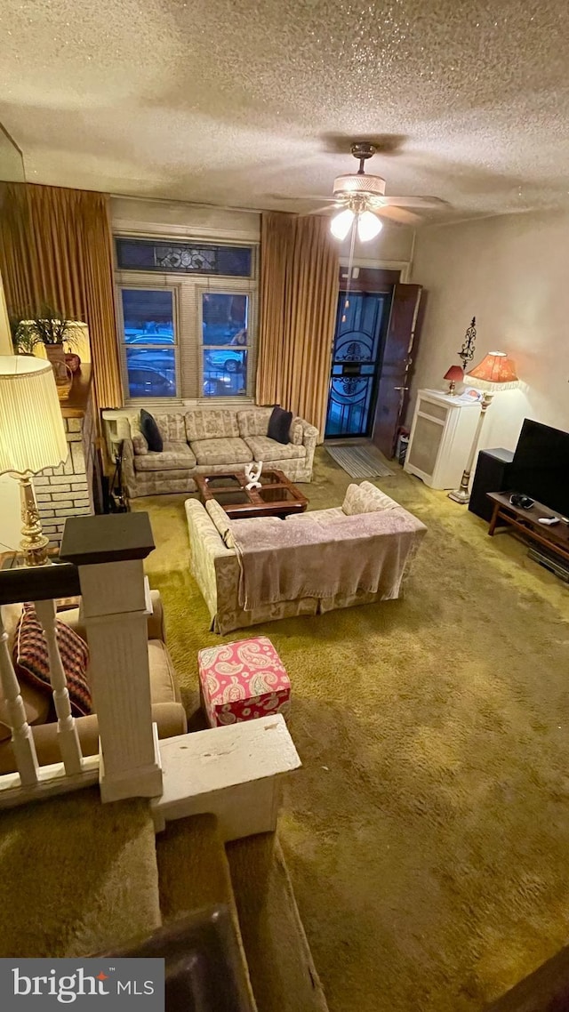 carpeted living room featuring ceiling fan and a textured ceiling