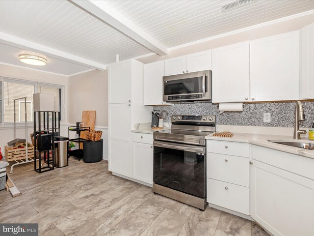 kitchen featuring decorative backsplash, appliances with stainless steel finishes, sink, beamed ceiling, and white cabinets