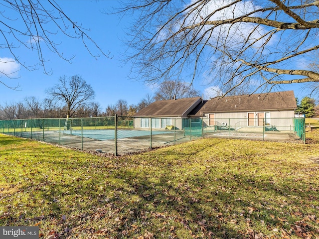 view of tennis court featuring a yard