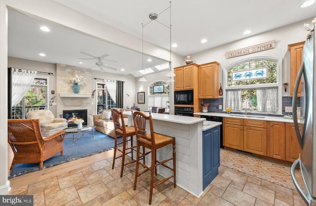 kitchen with black appliances, a kitchen island, a healthy amount of sunlight, and sink