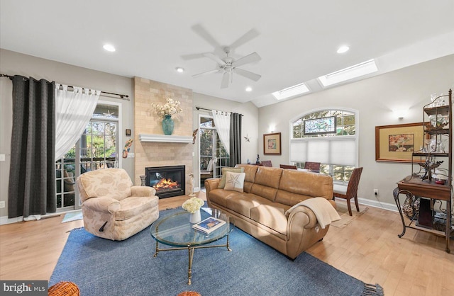 living room with a fireplace, light hardwood / wood-style flooring, a wealth of natural light, and ceiling fan