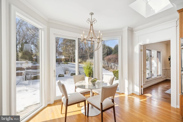 sunroom with an inviting chandelier and a skylight