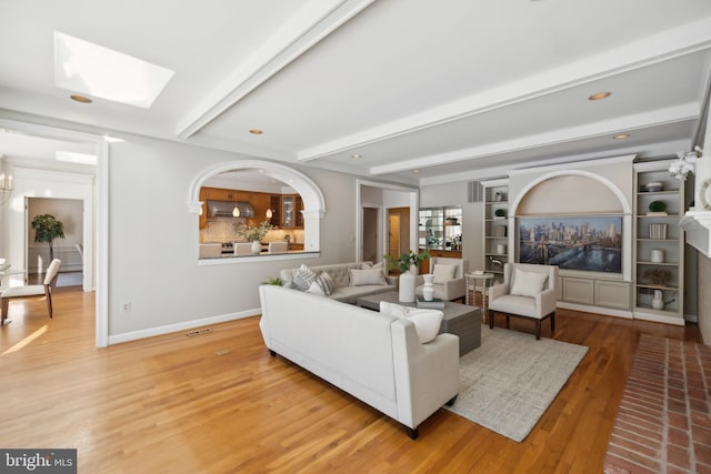 living room with hardwood / wood-style flooring, a skylight, and beam ceiling