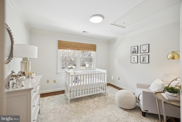 bedroom with crown molding, light hardwood / wood-style flooring, and a crib