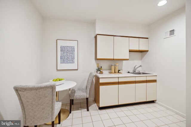 kitchen with white cabinets, sink, and light tile patterned floors