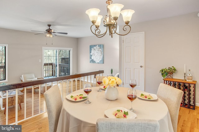 dining area with ceiling fan with notable chandelier and light wood-type flooring