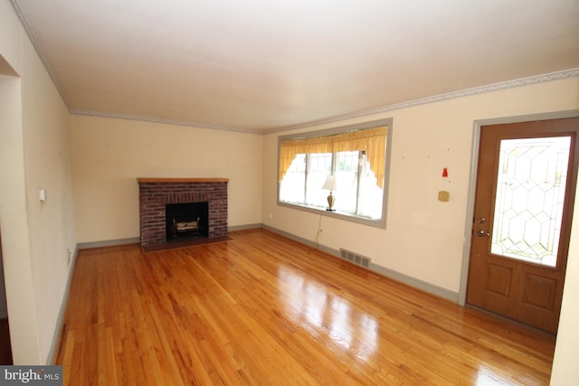 unfurnished living room featuring crown molding, light hardwood / wood-style floors, and a brick fireplace