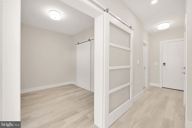 corridor featuring a barn door and light hardwood / wood-style floors