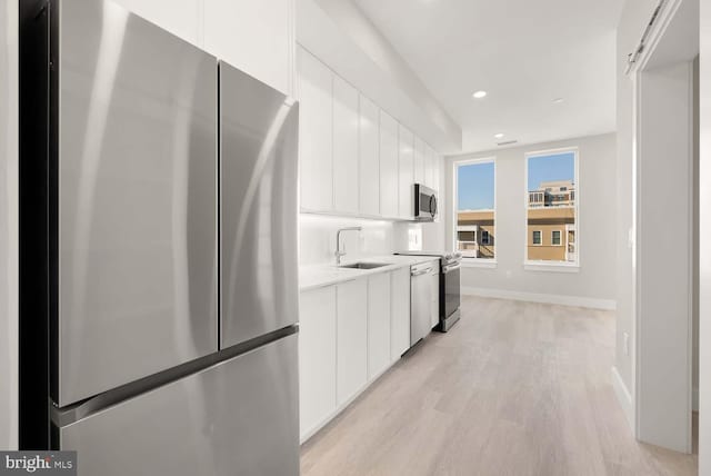 kitchen featuring white cabinets, light wood-type flooring, sink, and appliances with stainless steel finishes