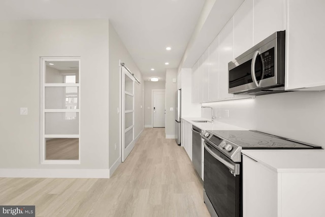 kitchen featuring white cabinets, light wood-type flooring, stainless steel appliances, and sink