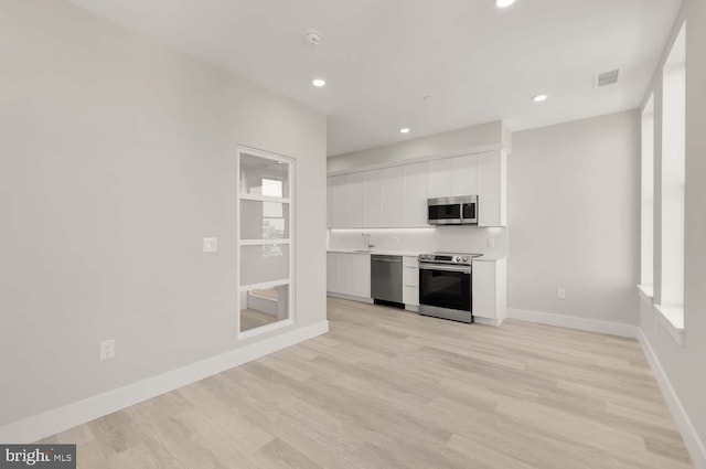 kitchen featuring a healthy amount of sunlight, white cabinets, sink, appliances with stainless steel finishes, and light hardwood / wood-style floors