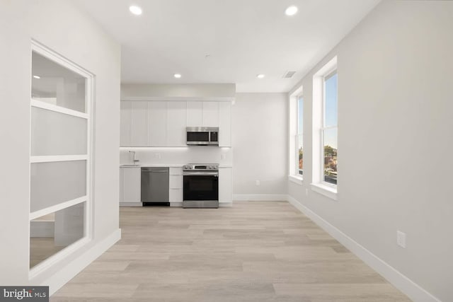 kitchen with white cabinetry, sink, light hardwood / wood-style floors, and appliances with stainless steel finishes