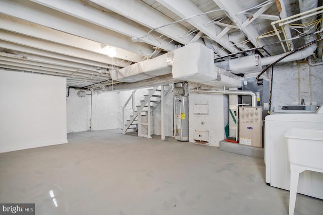 basement featuring washer and dryer, gas water heater, and sink