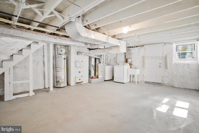 basement with gas water heater, washing machine and clothes dryer, electric panel, and water heater