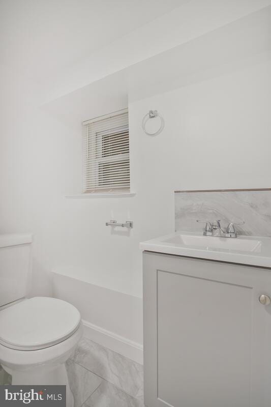 3917 Ridgewood Ave, Baltimore, MD 21215 - bathroom featuring marble look tiles, toilet, vanity, and a bath