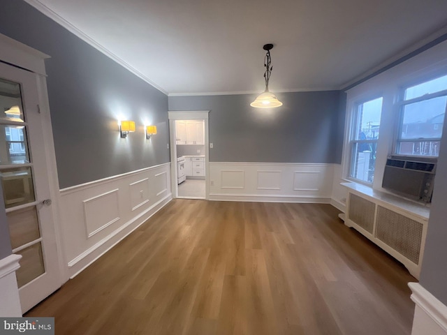 unfurnished dining area with crown molding, radiator heating unit, cooling unit, and light hardwood / wood-style flooring