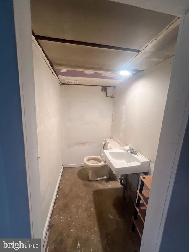 bathroom with concrete flooring, toilet, and sink