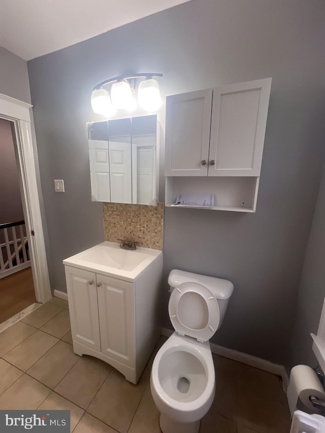 bathroom with tile patterned flooring, vanity, toilet, and backsplash