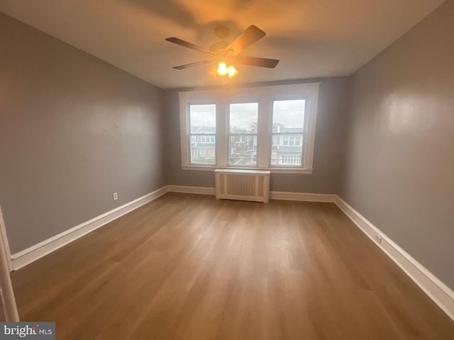 unfurnished room with radiator heating unit, ceiling fan, and hardwood / wood-style floors