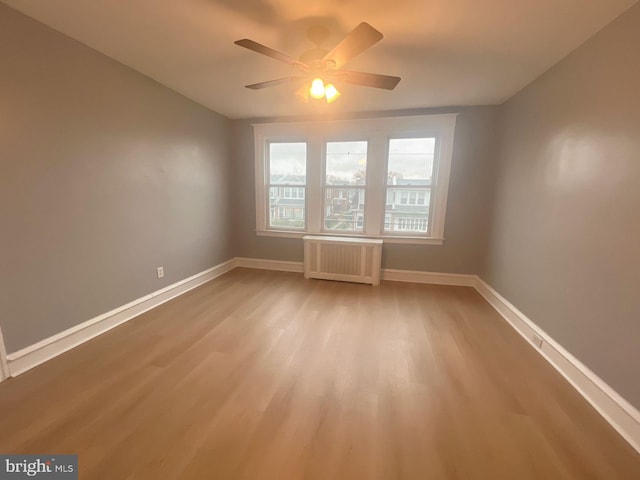 spare room featuring ceiling fan, radiator heating unit, and hardwood / wood-style flooring