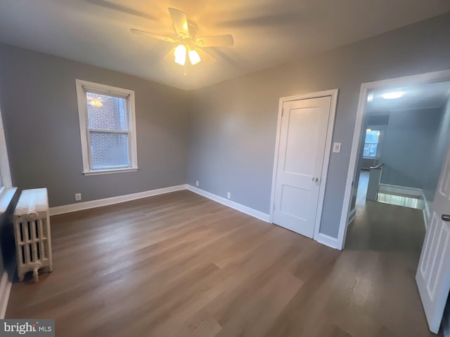 unfurnished bedroom with ceiling fan and dark wood-type flooring