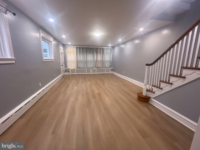 basement featuring baseboard heating, radiator heating unit, and light hardwood / wood-style floors