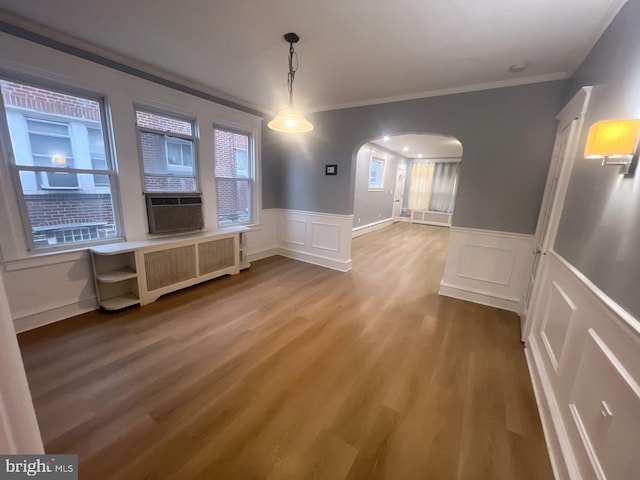 unfurnished dining area with wood-type flooring, radiator, and ornamental molding