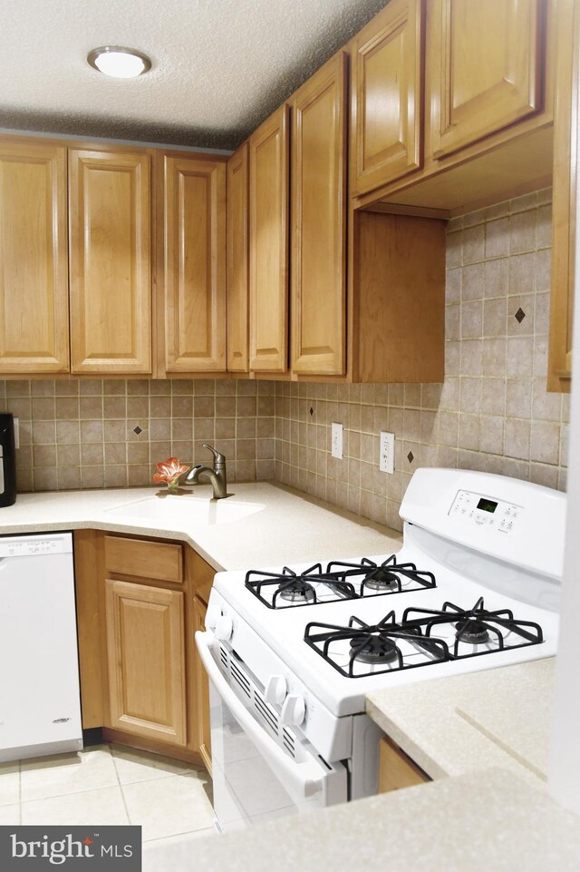 kitchen featuring white appliances, sink, light tile patterned floors, a textured ceiling, and tasteful backsplash