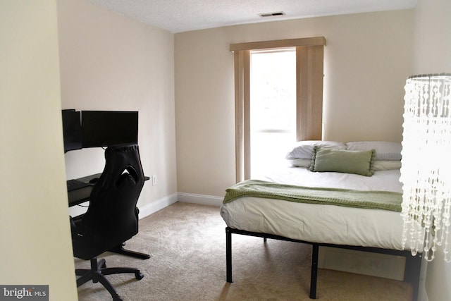 bedroom with light colored carpet and a textured ceiling