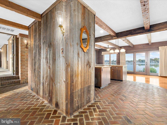 corridor with beam ceiling, a water view, and wooden walls