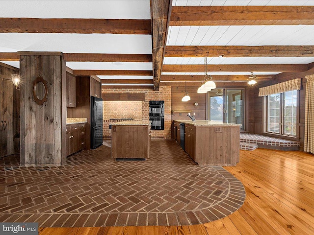 kitchen featuring ceiling fan, dark hardwood / wood-style flooring, decorative light fixtures, a center island with sink, and black appliances