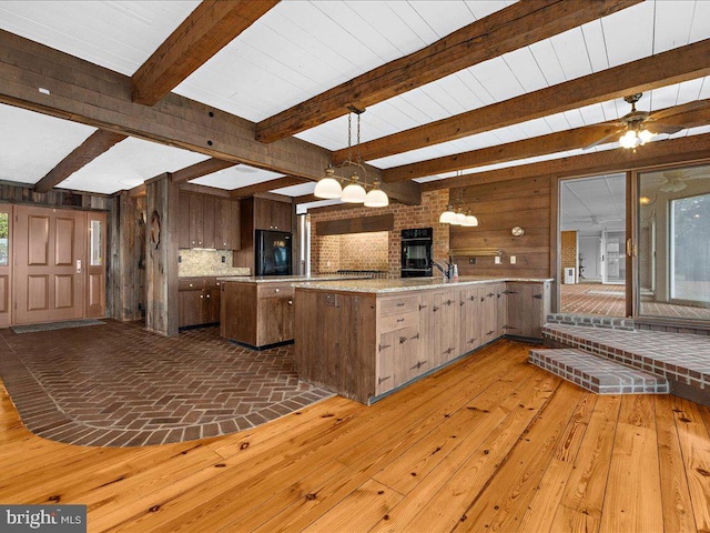 kitchen featuring kitchen peninsula, black fridge, light hardwood / wood-style flooring, and wood walls