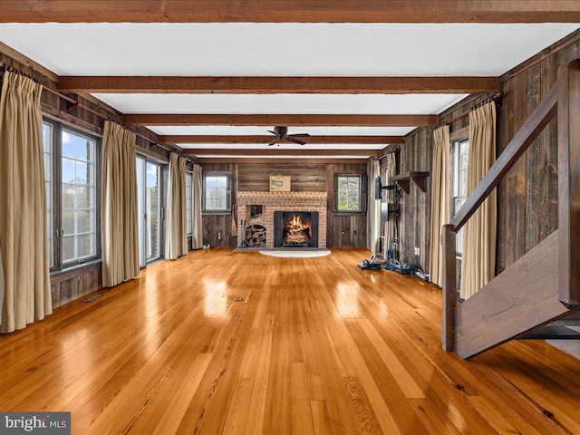 unfurnished living room featuring wood walls, light hardwood / wood-style flooring, plenty of natural light, and a brick fireplace