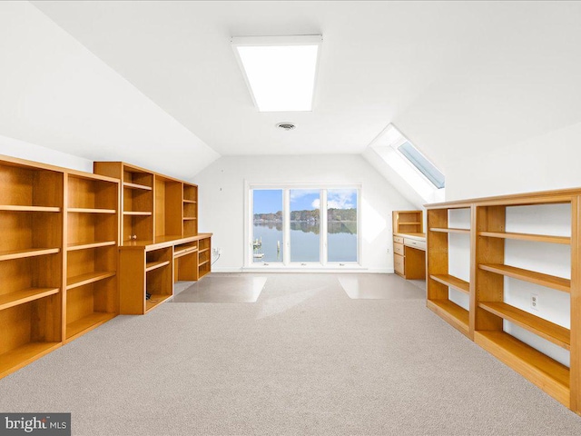 additional living space featuring light carpet and vaulted ceiling with skylight