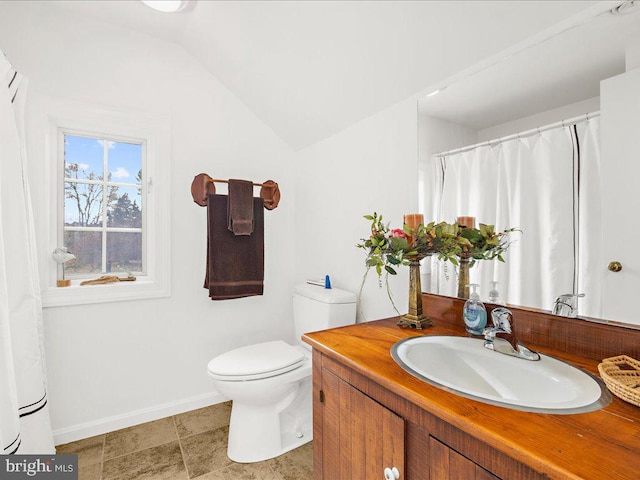 bathroom featuring vanity, toilet, and vaulted ceiling