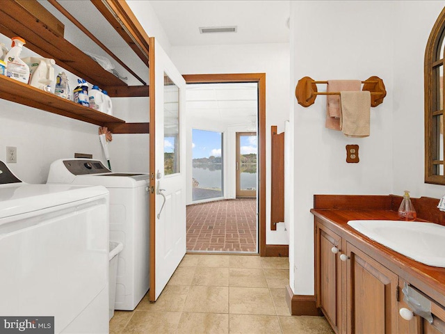 laundry area with separate washer and dryer, sink, and light tile patterned flooring