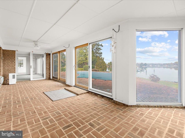 unfurnished sunroom with ceiling fan and a water view