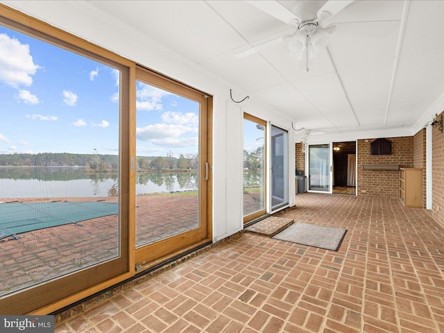 unfurnished sunroom with ceiling fan and a water view