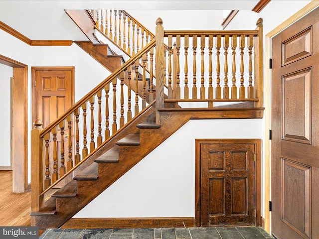 stairs with wood-type flooring and ornamental molding