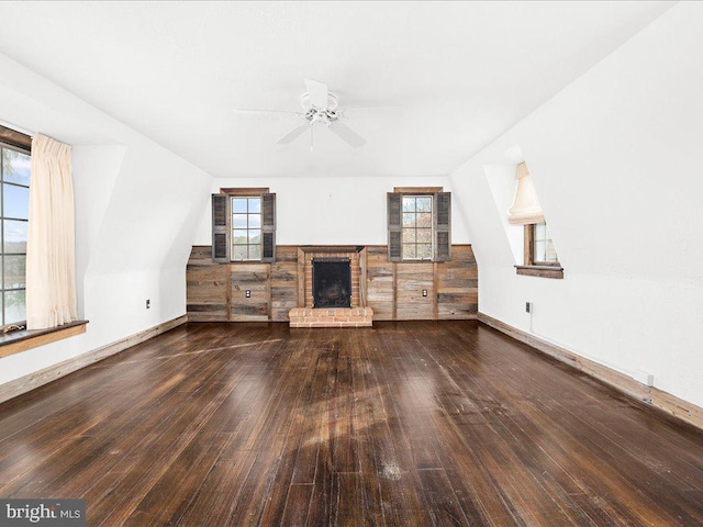 unfurnished living room featuring a fireplace, dark hardwood / wood-style flooring, and ceiling fan