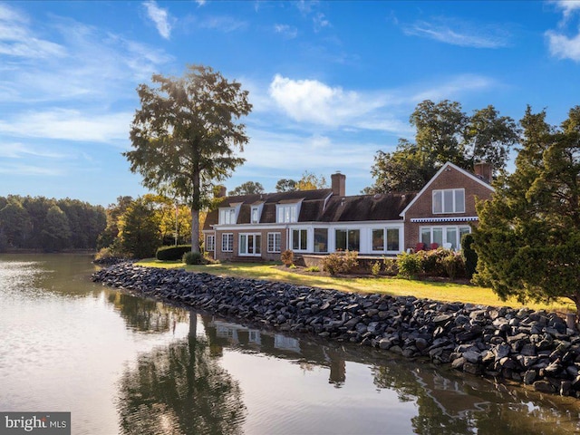 rear view of property featuring a lawn and a water view