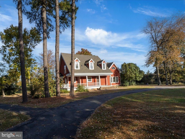 cape cod home featuring covered porch and a front yard