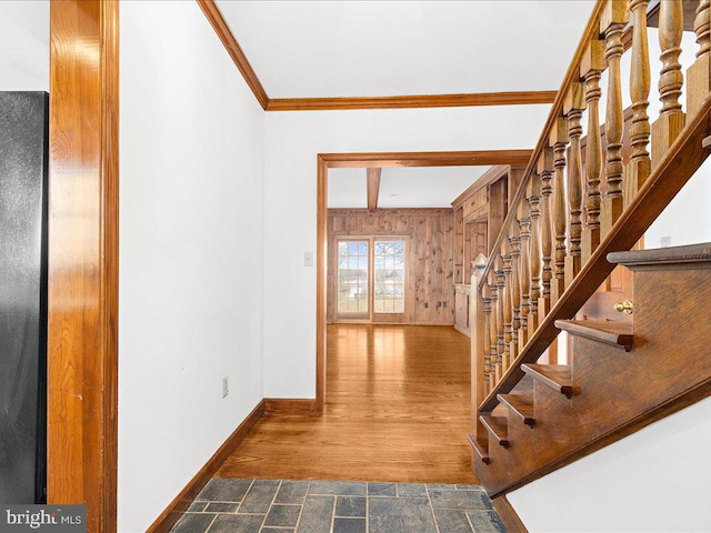 staircase with wood-type flooring, crown molding, and wooden walls