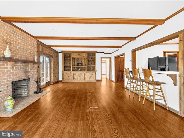 unfurnished living room with beam ceiling, crown molding, wood-type flooring, and a fireplace