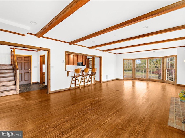 unfurnished living room featuring beam ceiling and dark hardwood / wood-style flooring