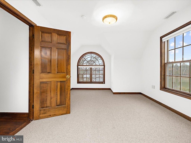 spare room with light carpet and lofted ceiling