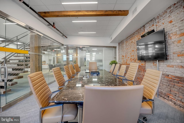 dining space featuring a drop ceiling and brick wall