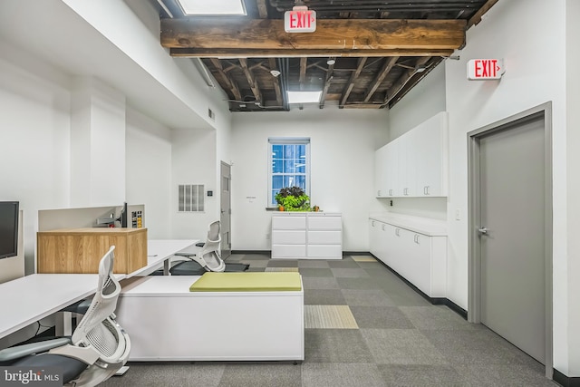 kitchen featuring beam ceiling, a towering ceiling, white cabinets, and dark colored carpet